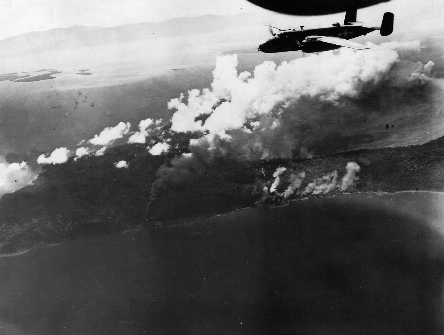 A B-25 Mitchell of the 13th Air Force roars above burning Japanese oil installations in New Britain. A B-25 Mitchell of the 13th Air Force roars above burning Japanese oil installations in New Britain.